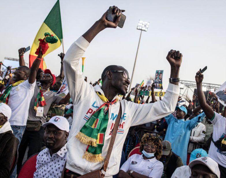Apoiadores do candidato presidencial da oposição Bassirou Diomaye Faye e do líder da oposição Ousmane Sonko comemoram durante seu último comício de campanha em Mbour, Senegal, em 22 de março de 2024. (John Wessels / AFP via Getty Images)